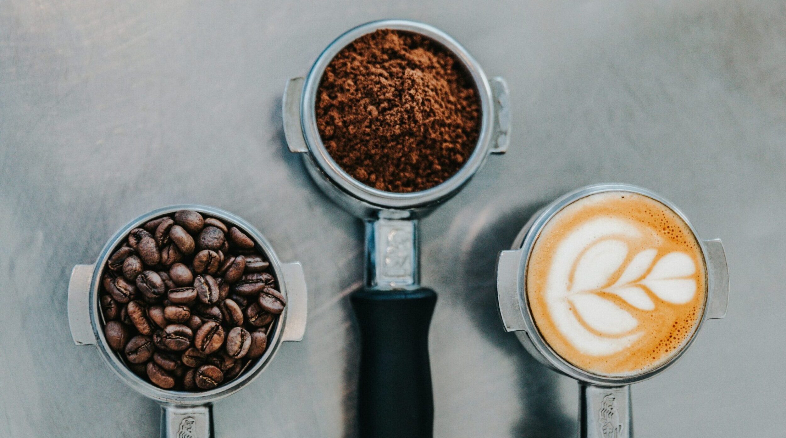 trois moulures de cafe une avec graine moulu , une avec un late et la dernière avec des grains de cafe 